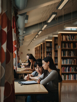 Des élèves étudiant ensemble à une table dans une bibliothèque.