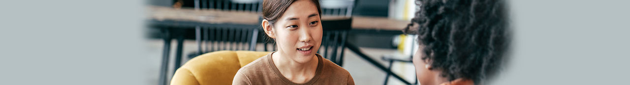 Woman writing on notepad talking to coworker